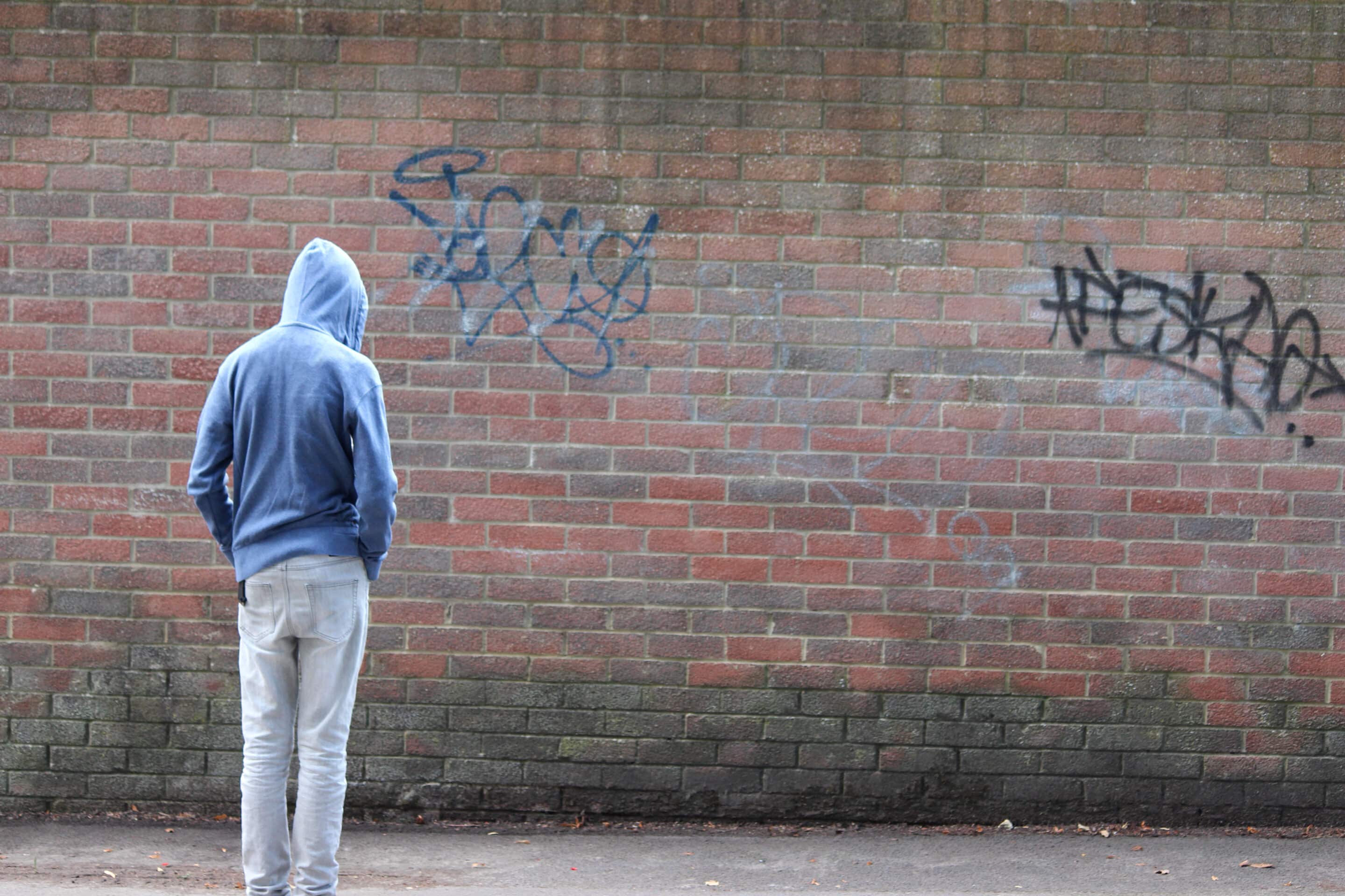 Image Of Teenage Boy / Youth Wearing Hoodie, Beside Graffiti Wall