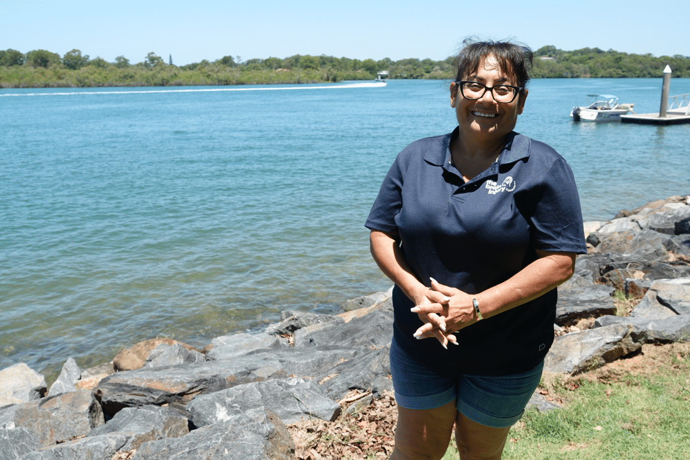 Angela Kalantzis stands beside the Tweed River smiling to the camera
