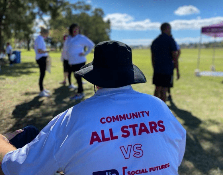 Shows the back of a t-shirt with Community All Stars vs Social Futures
