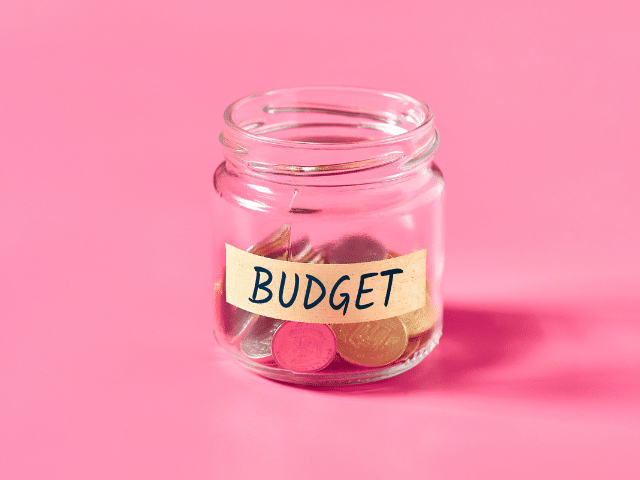 Image shows a jar of coins with the word BUDGET written on it.