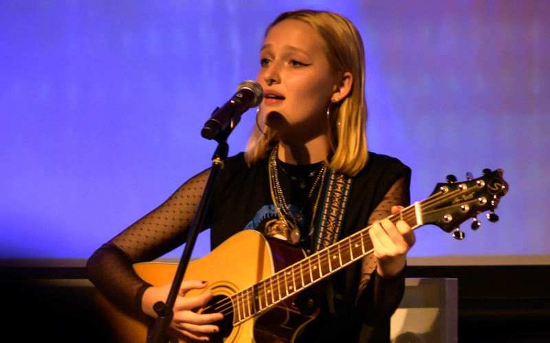 Mia French performing on guitar and singing