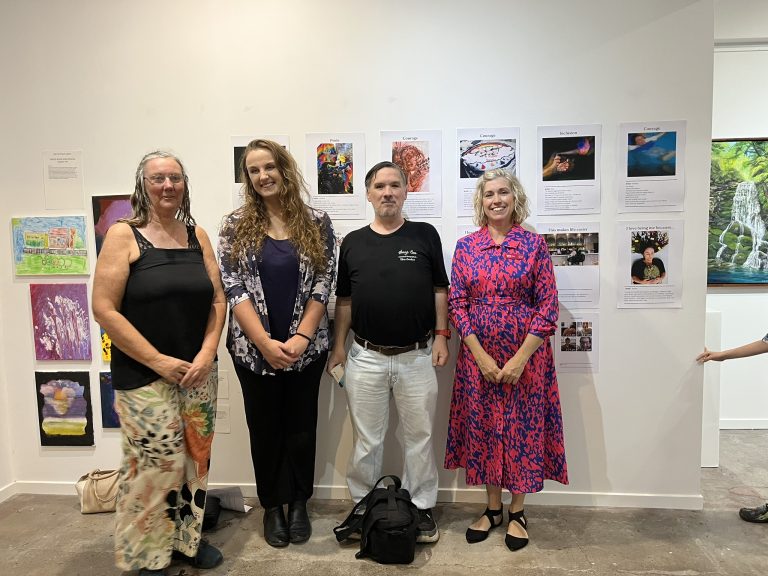 Art Without Limits Photovoice Artists standing in from their art with Local Area Coordinator Gemma