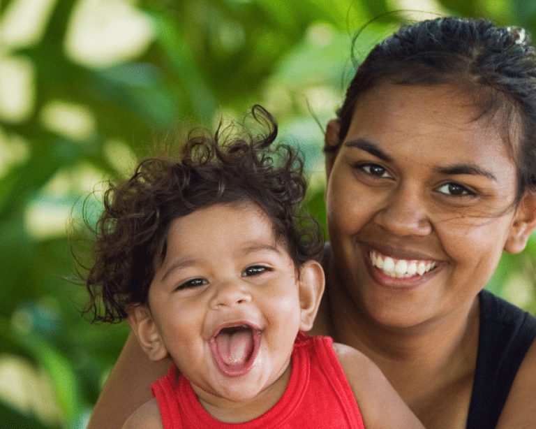 First Nations mum smiling and holding baby