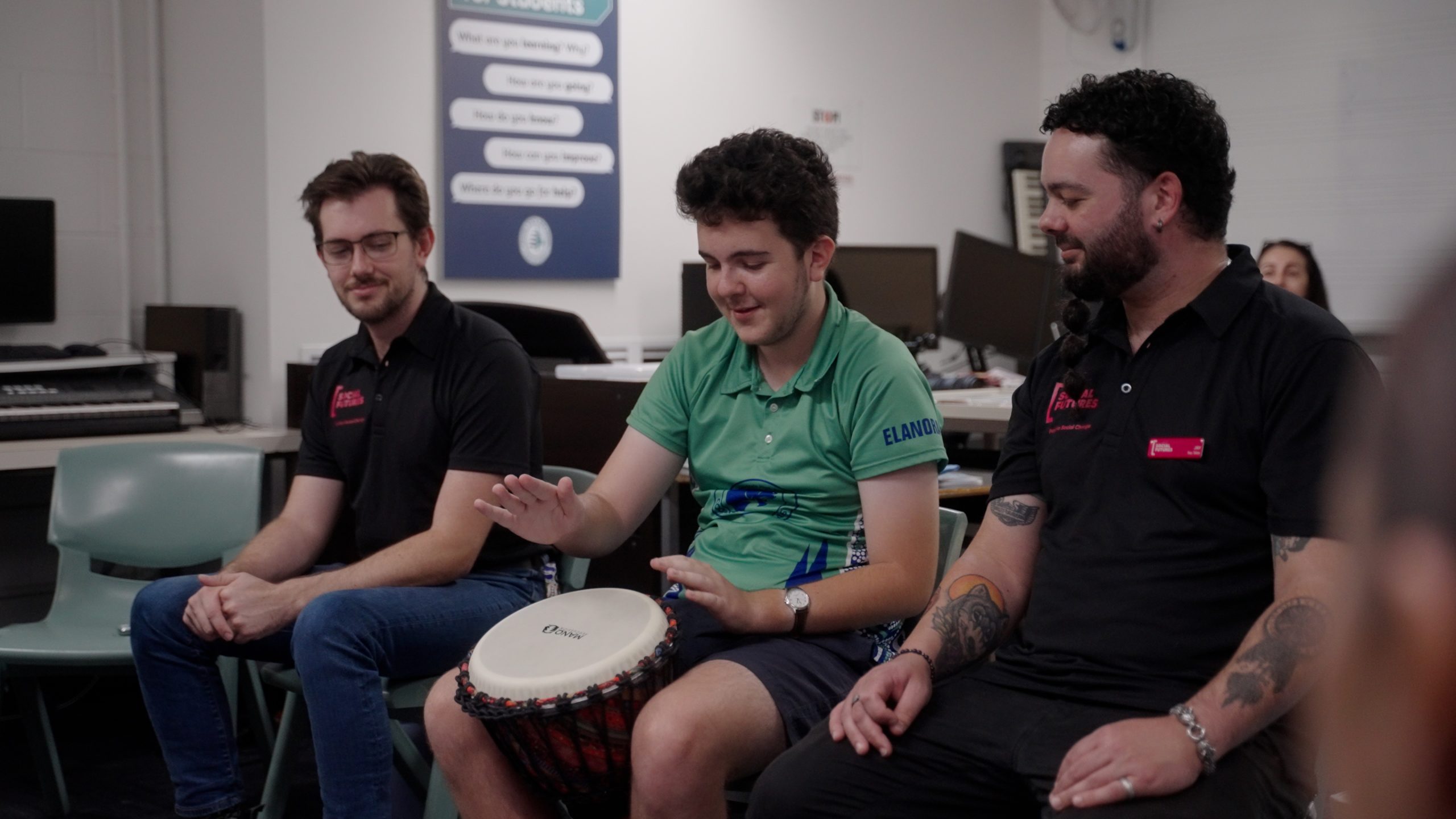student playing the drums with peer mentors Jay and Jake