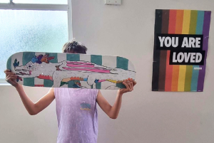 Child in Queer Family Sprouts holding decorated skateboard