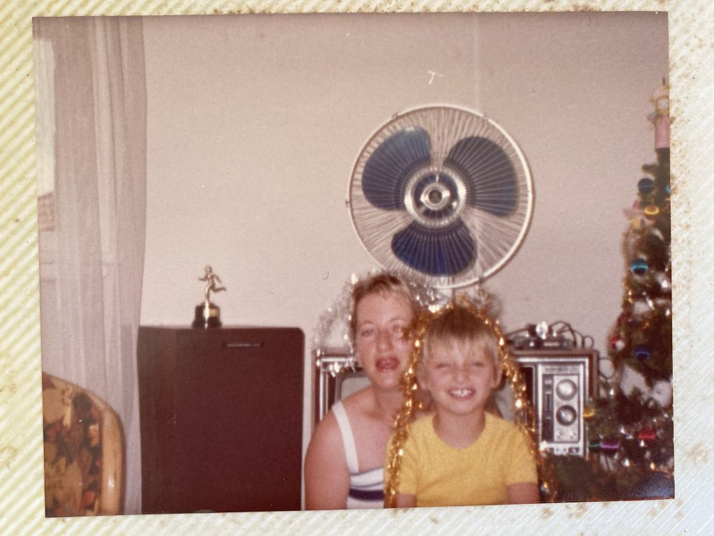 Image shows Karissa as a 9 year old with her Mum at Christmas, 1984. They are both wearing tinsel on their heads. 