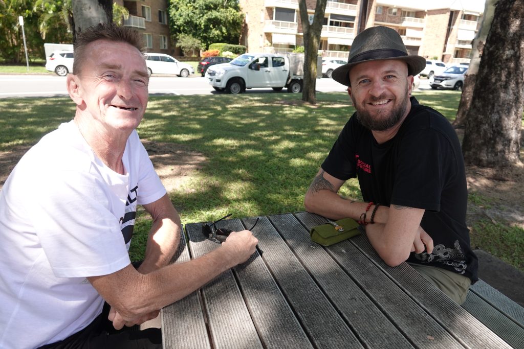 Richard and Sacha sit together on an outdoor bench