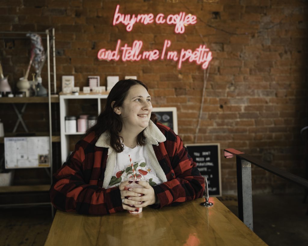 Oceanlee sits at a cafe table