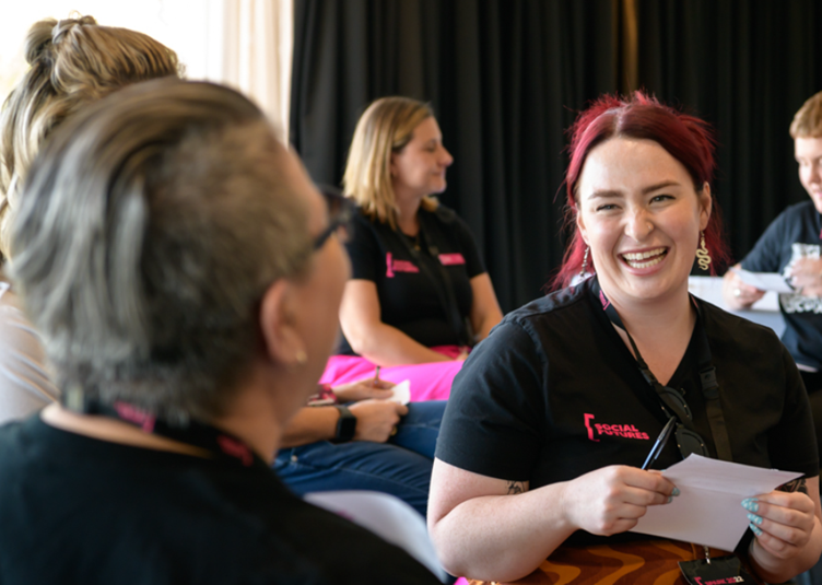 Shows a woman with red haor wearng a social futures t shirt, laughing