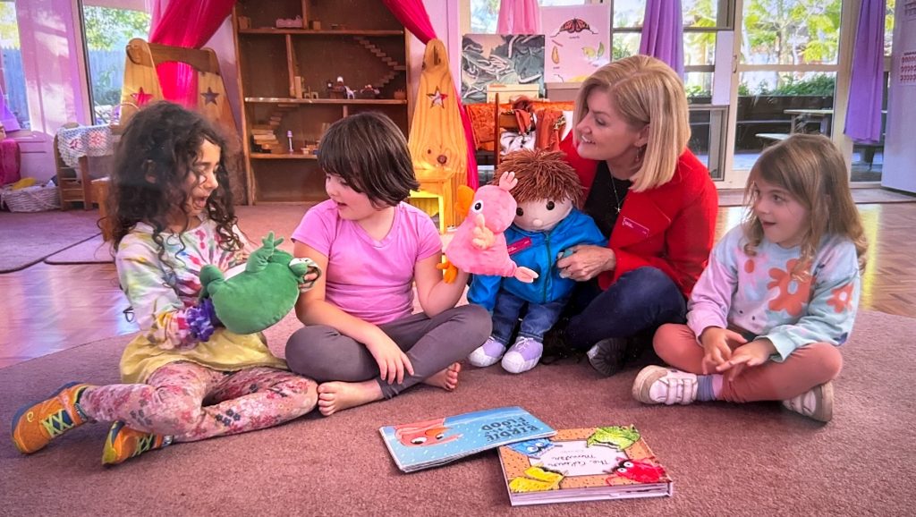 Lisa Wilson, Jack and Three Children sit on the floor with books and puppets