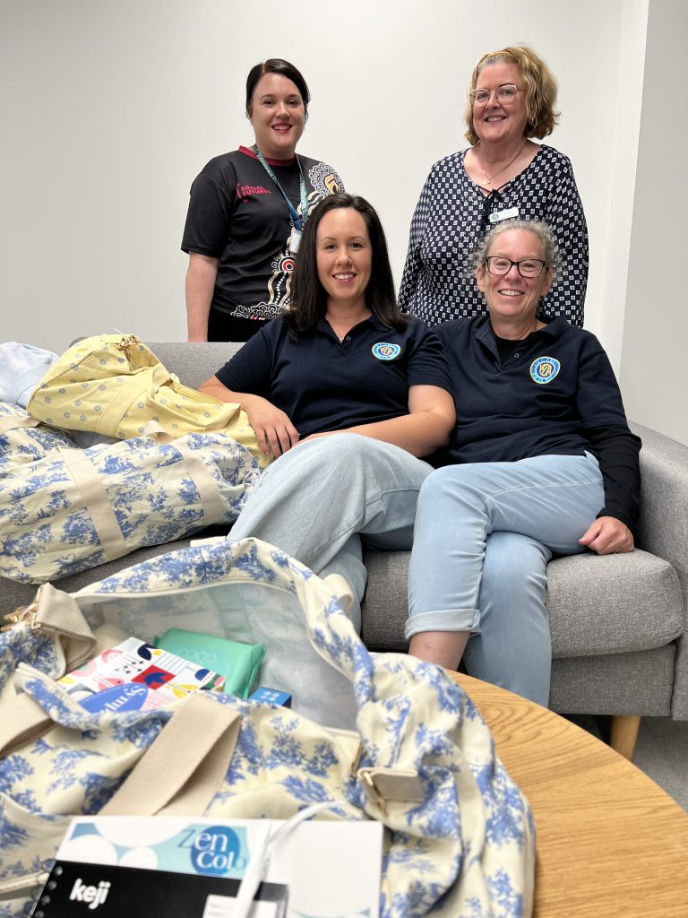 Four women sit on a couch with toileteries in a bag in the foreground